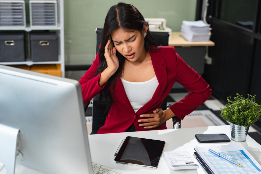 Diarrhea or constipation, problems with health concept. closeup woman sitting desk headache and feeling pain in stomach touching it with hands having abdomen disease and illness.